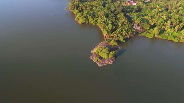 Aerial drone view of a beautiful Kerala landscape featuring a sandy beach, small coastal village, and calm Kerala Backwaters.