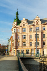 Obraz premium A large building in city Pilsen in Czech Republic with a green roof and a green spire. The building is pink and has a lot of windows