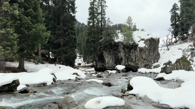 Scenic natural beauty of Chandanwari Valley featuring rocky landscapes, flowing streams, snow patches, and majestic Himalayan mountains near Pahalgam, Kashmir.