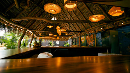 Resort bar featuring a thatched roof, decorative bamboo lights, and vibrant jungle murals, creating a relaxing vacation atmosphere
