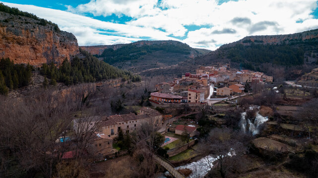 Aerial perspective of the historic village of Calmarza in the province of Zaragoza, showing its traditional houses with red-tiled roofs nestled peacefully in the green landscape of the Mesa River
