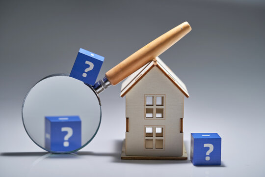 magnifying glass and model house  with cube block question mark