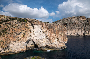 Iconic Blue Grotto sea arch in Malta - panoramic coastal view. Description: High-angle scenic view of the famous Blue Grotto on the southern coast of Malta, near Żurrieq. The image showcases the massi