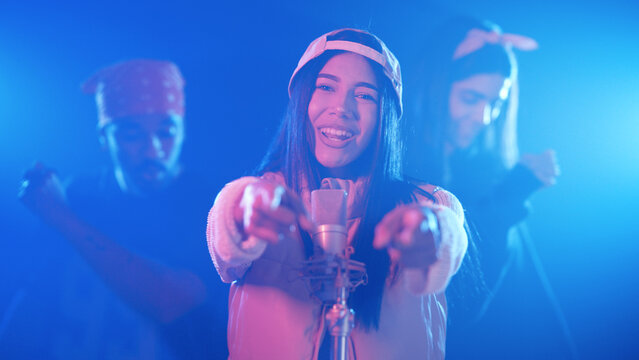 Talented female singer performing a live concert with background dancers, illuminated by vibrant blue and pink neon stage lights