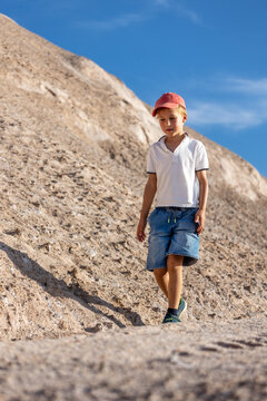 Young little boy walking along rocky slope clear blue sky show independence curiosity calm confidence outdoor summer adventure. Natural stone landscape sunlight travel lifestyle childhood exploration