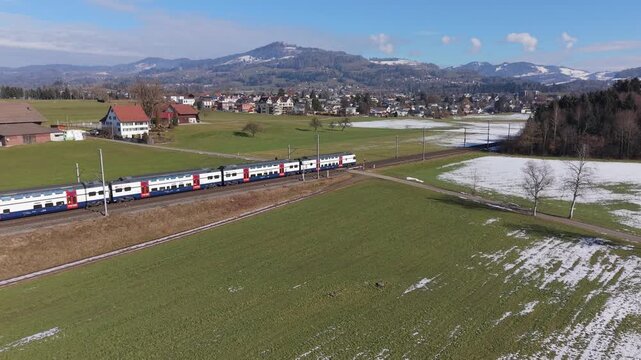 Scenic railway journey in Switzerland, a modern train moving against a stunning mountain backdrop.