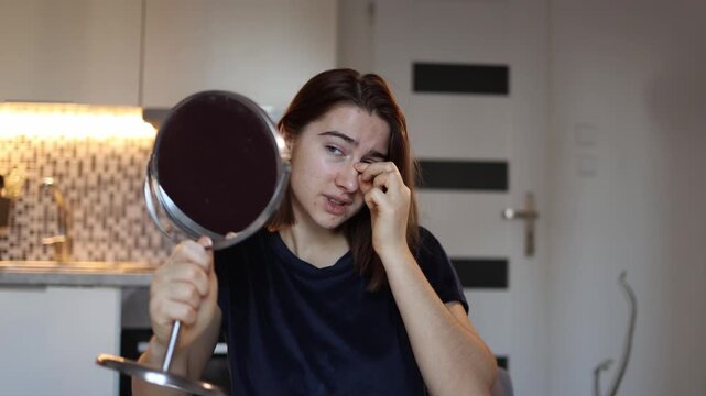 Young woman looks at her nose in mirror feeling dissatisfied and insecure about appearance honest self image struggle home lifestyle emotional beauty moment