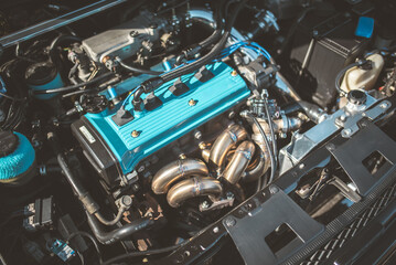 Fototapeta premium Close-up of a car engine with a custom blue valve cover and headers
