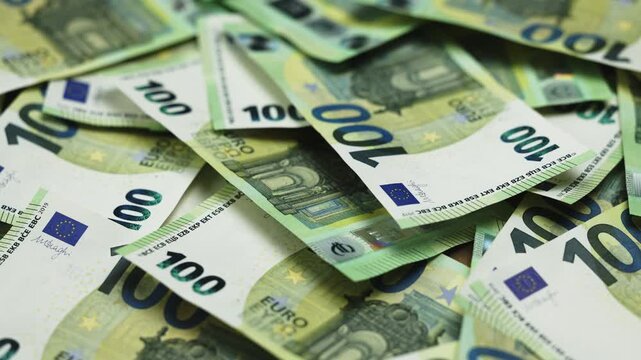 Macro close-up of many 100 euro notes focusing on fine details, security elements and texture, illustrating wealth and cash money concept.