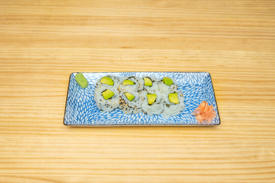 Sushi platter with inside-out rolls of various styles, some wrapped in fish slices and others with black or red sesame seeds.