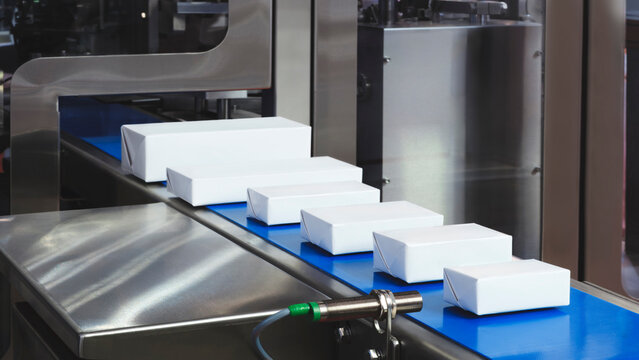 Conveyor belt of industrial packaging machine with white boxes. Industrial concept background
