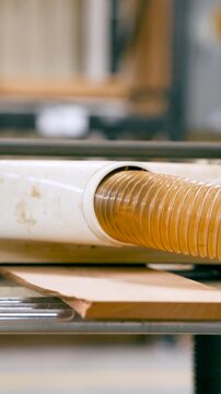 Close up of a woodworker operating a thickness planer machine. The skilled craftsman feeds a wooden board into the tool for processing. Vertical