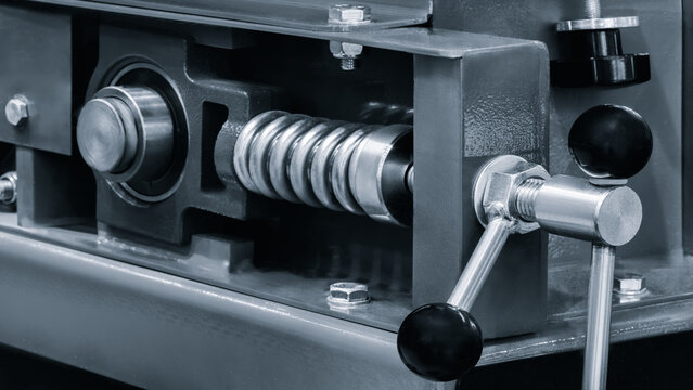 Machine with control handle for pressure on spring mechanism that controls speed of rotation of  metal shaft in frame with bearing as part of  large industrial machine and mechanism.