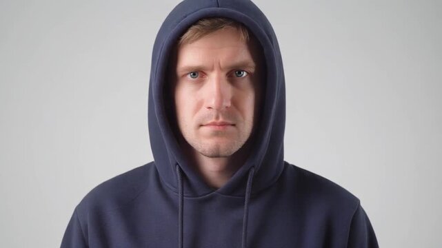 Man in hoodie with angry expression against plain background