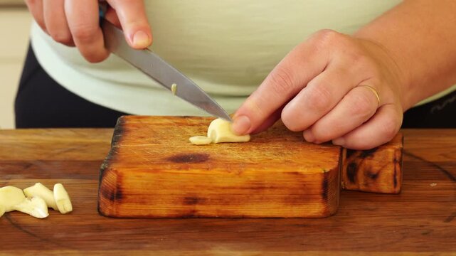 Woman is peeling and cutting garlic for cooking

