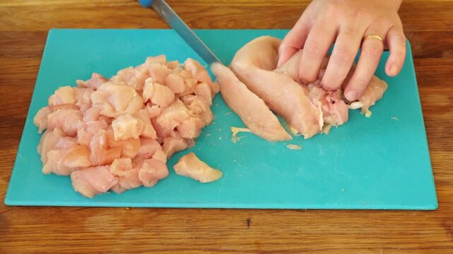 Woman cutting chicken fillet for cooking
