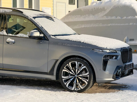 Metallic gray BMW X7 G07 in the street parking lot. The modern vehicle exterior SUV car BMW X7 G07. Premium Germany SUV Car BMW X7 G07 covered snow in the street parking.