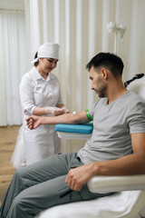 Obraz premium Nurse preparing arm for blood draw procedure, collecting test sample from male patient for medical diagnostic purposes in clinical laboratory setting. Concept of healthy lifestyle.