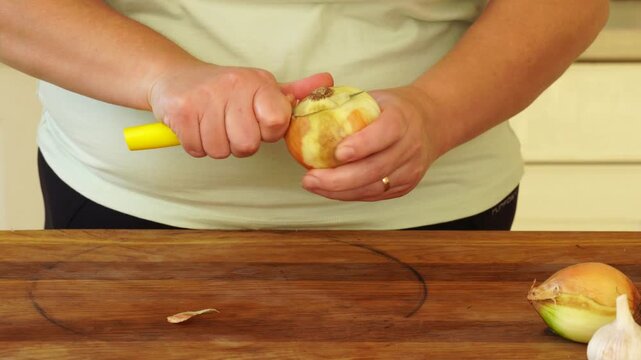 Woman is peeling and cutting onions for cooking
