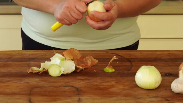 Woman is peeling and cutting onions for cooking
