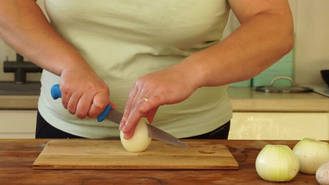 Woman is peeling and cutting onions for cooking
