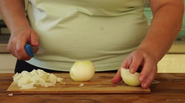 Woman is peeling and cutting onions for cooking
