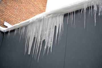 Icicles under the roof of a house in winter © Oxana