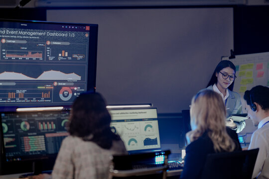 Dynamic night ops hub action Diverse team collaborates intensely analyzing critical data screens leader provides guidance modern command center buzz achieves mission goals now teamwork boost.