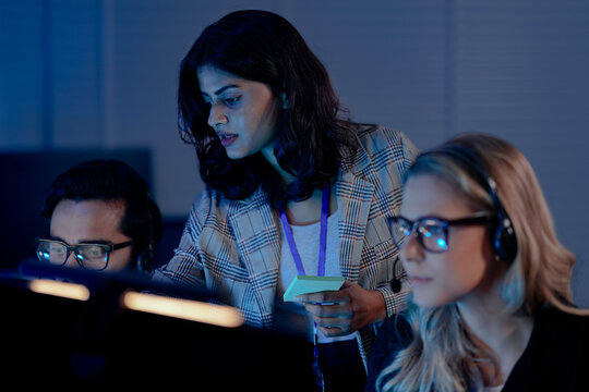 A future call center manager uses an AI platform showing predictive analytics on agent performance, identifying coaching needs in real time for optimized customer interactions.