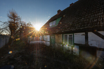 Stary dom z muru pruskiego na tle zachodzącego słońca © Magdalena