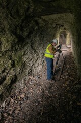 Fototapeta premium Worker Measures Structure in Underground Tunnel During Day Light Hours