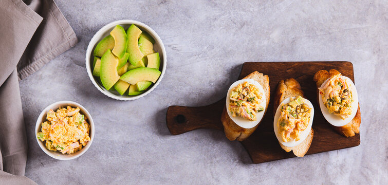Canapes with deviled eggs on toast on a board on the table top view web banner