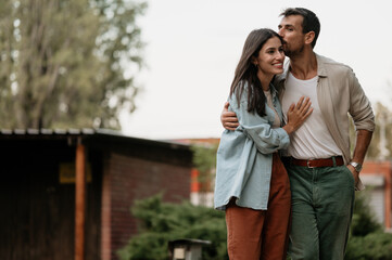 Fototapeta premium Happy couple sharing a tender moment outdoors, man kissing woman on forehead