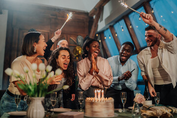 Diverse friends celebrating birthday party, happy people gathering with cake, candles, and sparklers