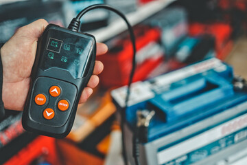 Mechanic uses handheld diagnostic tool to test car battery health and performance