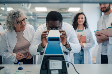Diverse research team working with microscope in laboratory