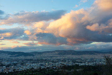 Athens (Greece) at sunset with beautiful clouds. 
Fluffy pink clouds hang over the city