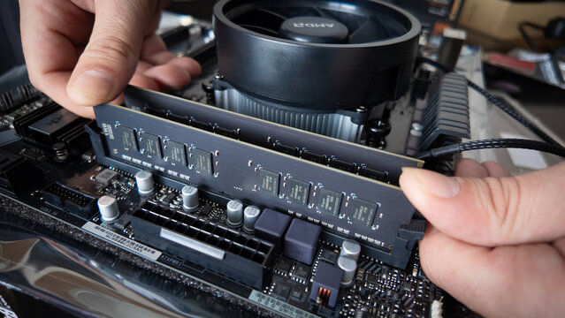 RAM memory module being installed into a motherboard during desktop computer assembly, amid increased memory prices and market demand.