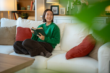 Obraz premium Woman relaxing at home, enjoying a good book
