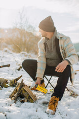 Man starting campfire with gas torch in snow