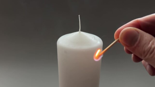 Lighting white paraffin thick round candle with matches close-up