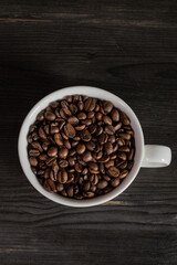 Fototapeta premium White coffee cup filled with coffee beans, minimal still life, clean background, coffee concept.