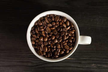 Fototapeta premium White coffee cup filled with coffee beans, minimal still life, clean background, coffee concept.