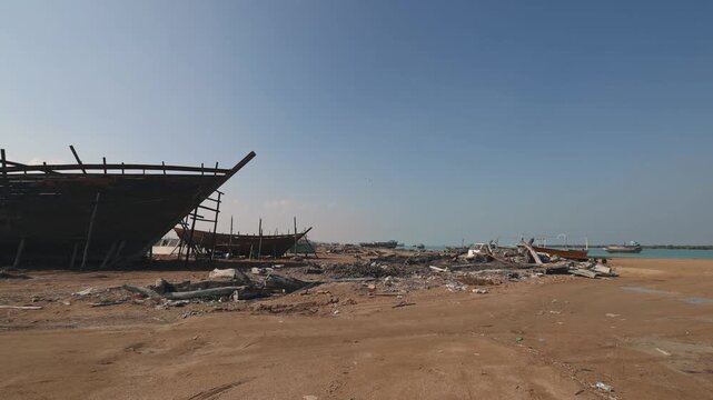 Construction of a wooden ship. Shipyard of traditional Dhow wooden boat on Iranian Qeshm Island. Tradition Lenj Fishing Boat in Qeshm Island in Southern Iran. Old wooden stealth smuggler's ship.