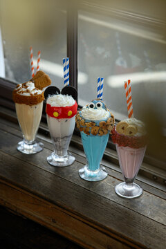 Four different types of milkshakes with different toppings and straws
