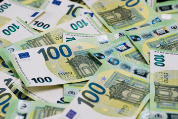 Obraz premium Close-up view of scattered 100 euro banknotes on a flat surface, showcasing intricate designs and security features of European currency in a detailed arrangement