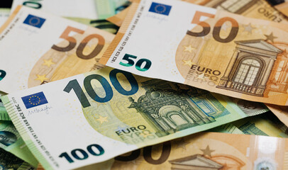 Obraz premium Close-up view of assorted Euro banknotes including fifty and one hundred denominations arranged on a flat surface with intricate designs and colors visible