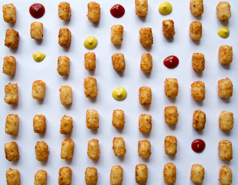 Tater tots with ketchup and mustard arranged in a pattern