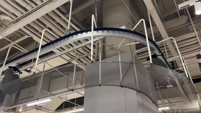 captures suspended conveyor system with curved section, support rods, and guard netting inside distribution area. Material handling equipment highlights sorting, order processing, and warehouse