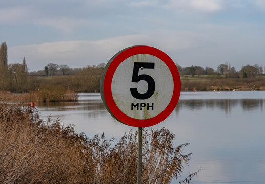 Close and selective focus on a 5mph speed sign on the entrance to Rockingham Broad, Norfolk Broads